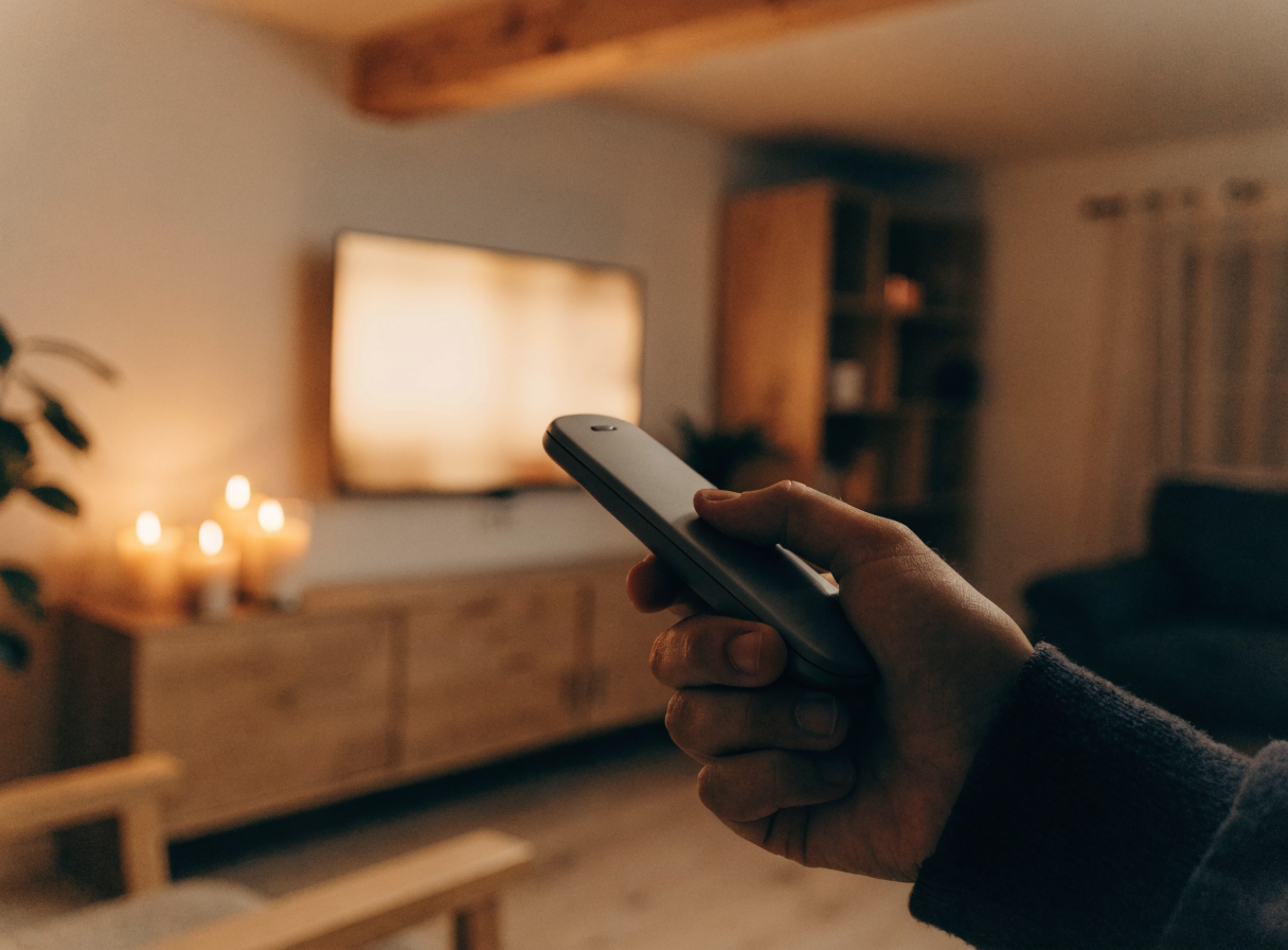 Hånd peger fjernbetjening mod et Smart TV under opsætning af IPTV Dansk